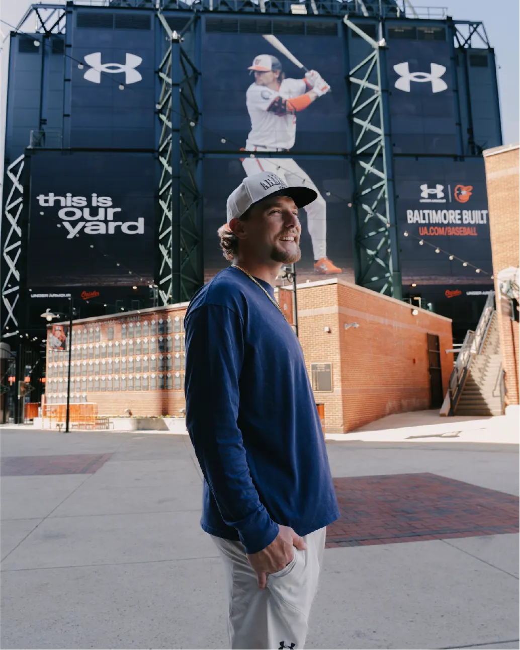 Gunnar Henderson stands below giant Under Armour Billboard facing Eutaw Street on backside of New LED Scoreboard at Camden Yards