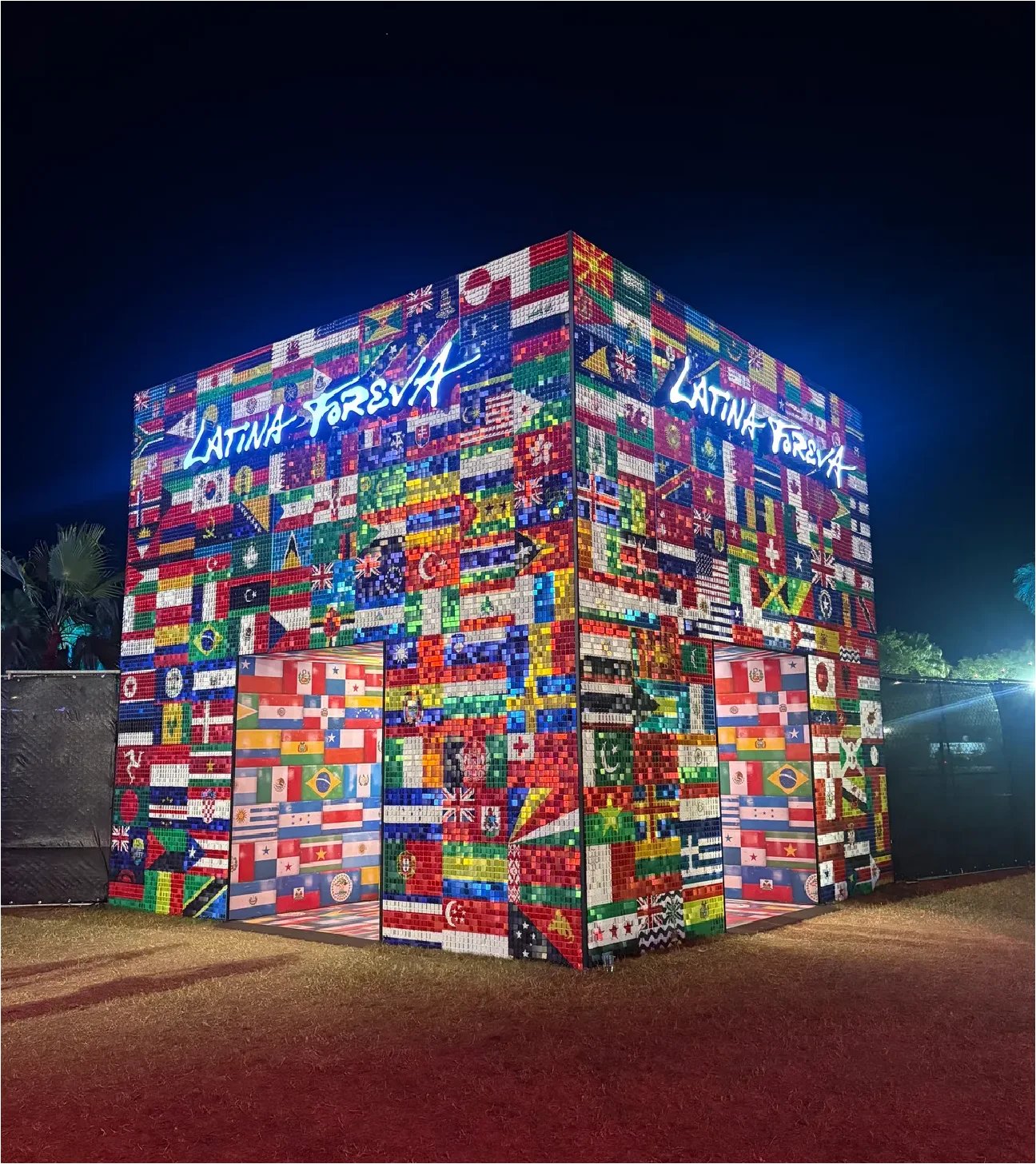 Exterior view of the Karol G LED cube covered with various international flags at Coachella 2026